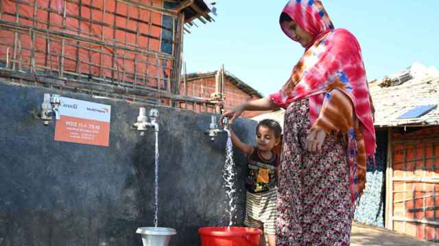 Una mujer y su hijo cogiendo agua de una fuente en Bangladesh.