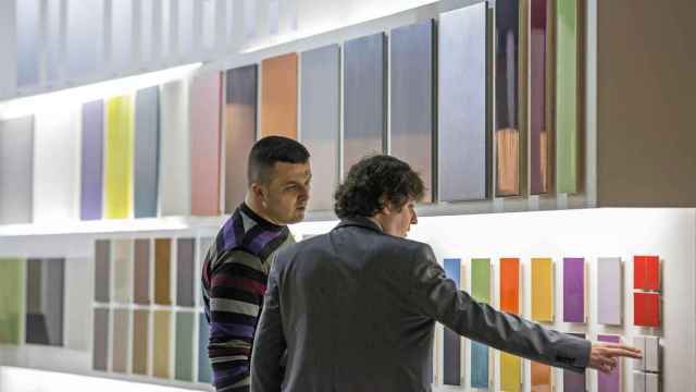 Una persona enseñando diversas muestras de azulejo a un posible comprador, en imagen de archivo.