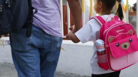 Un padre lleva a su hija al colegio en el primer día de curso.