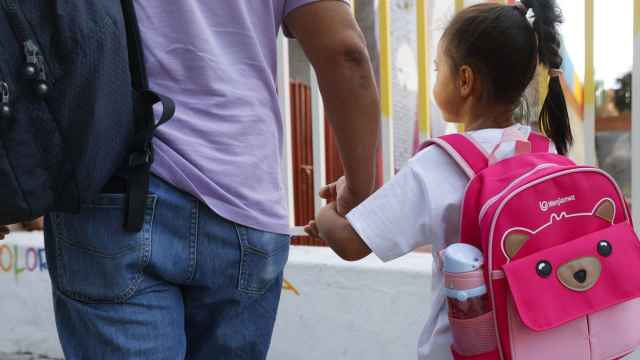 Un padre lleva a su hija al colegio en el primer día de curso.