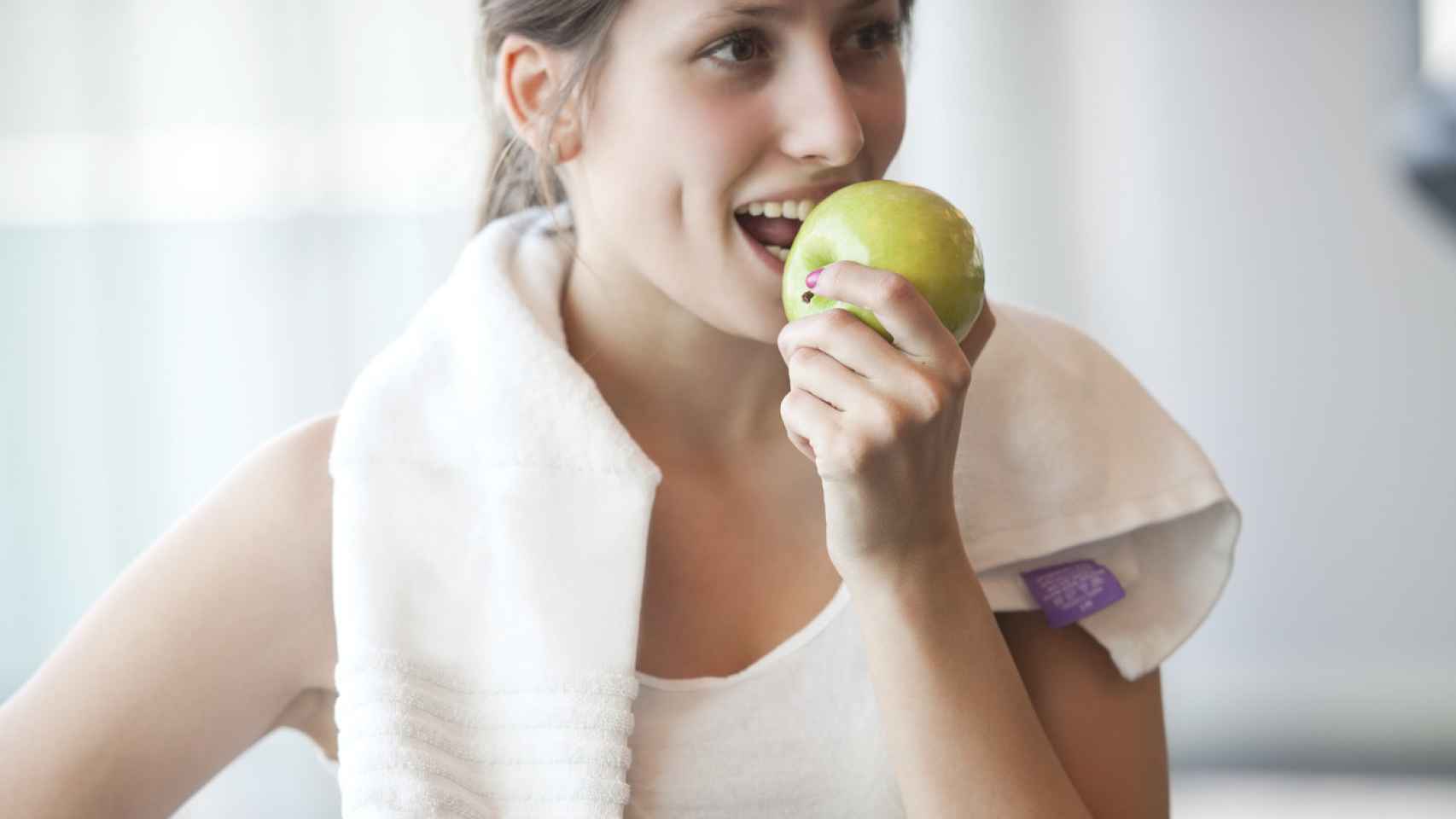 Mujer comiendo manzana en una ruptura de ejercicios. Fuente: iStock.