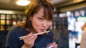 Mujer joven comiendo en un viejo restaurante japonés.