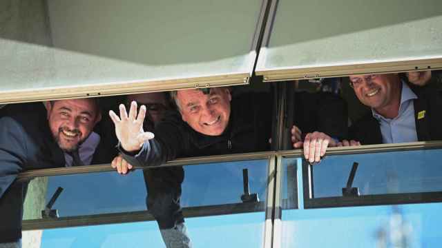 El expresidente brasileño Jair Bolsonaro saluda desde una ventana en la sede de su partido hoy, en Brasilia (Brasil).