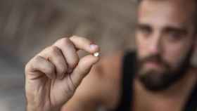 Imagen de archivo de una persona sosteniendo un fármaco entre sus dedos.