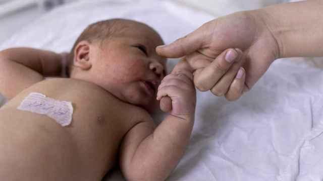 Un recién nacido coge el dedo de una enfermera.