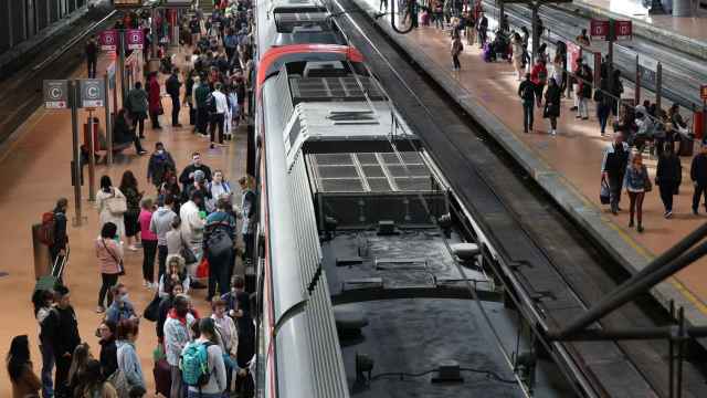 Numerosas personas con maletas esperan el pasado viernes en el andén la salida de un tren en la estación Almudena Grandes-Atocha Cercanías.
