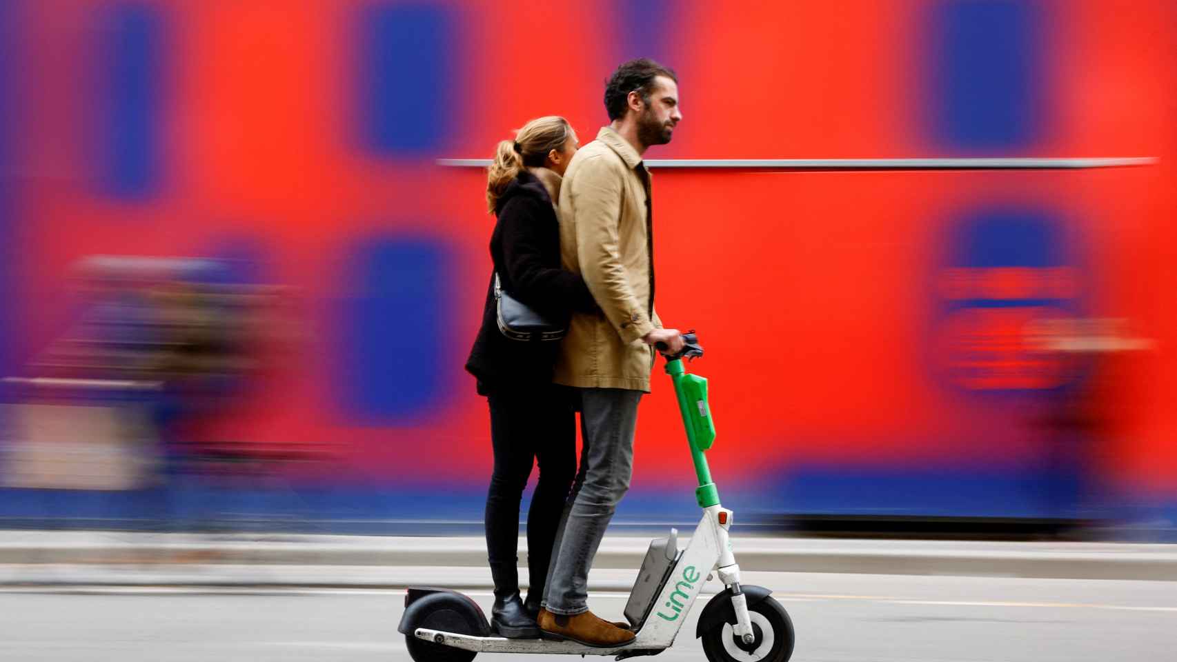 Dos personas se montan en un mismo patinete en París.
