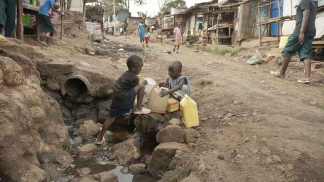Imagen de archivo de dos niños recogiendo agua en una calle de Kibera en Nairobi (Kenia).