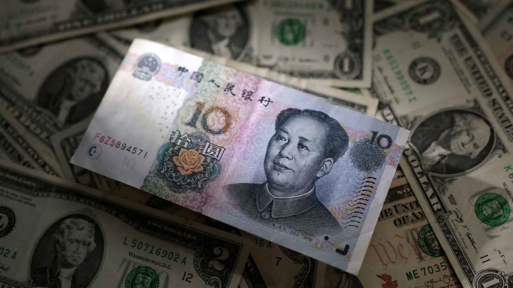 Diez yuanes chinos sobre varios billetes de dólar estadounidense.