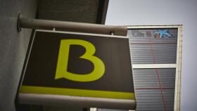 Un cartel con el símbolo de Bankia delante del logo de Caixabank tras su sustitución por el de Bankia en las torres Kio, en Madrid (España).
