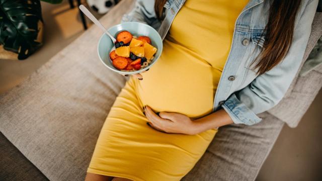 Mujer embarazada comiendo fruta.