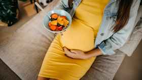Mujer embarazada comiendo fruta.