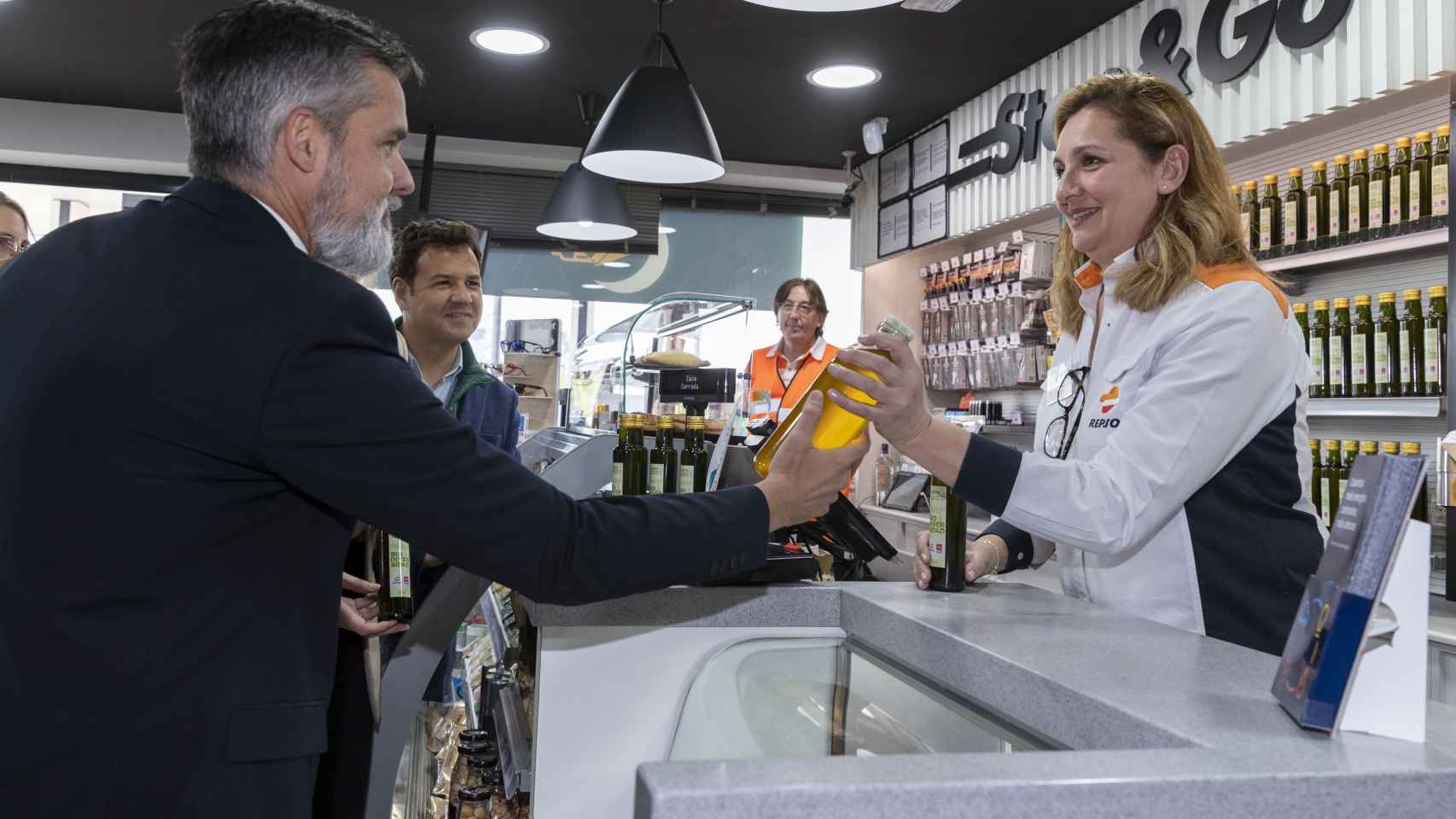 El Director General del área Cliente de Repsol, Valero Marín, entrega una botella de aceite de cocina usado en una estación de servicio de la compañía.