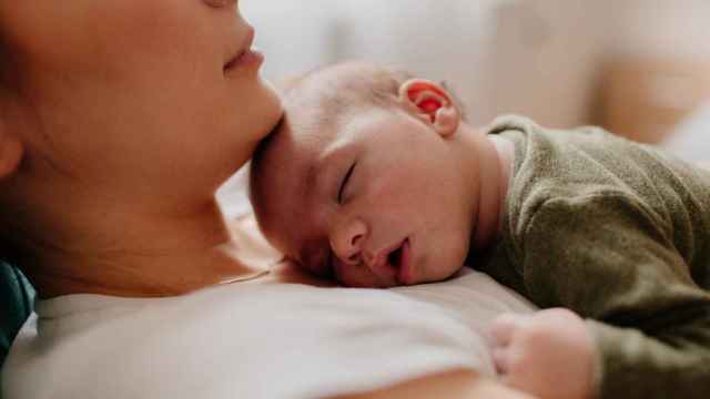 Una mujer duerme a su bebé sobre su pecho.