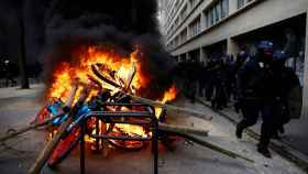 La policía antidisturbios pasa frente a objetos en llamas en medio de los enfrentamientos con manifestantes durante el undécimo día de huelgas y protestas nacionales contra la reforma de pensiones del Gobierno francés, en París, Francia.