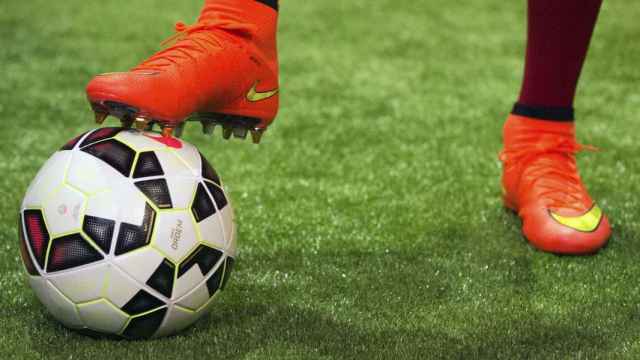 Balón de fútbol junto a la bota de un jugador