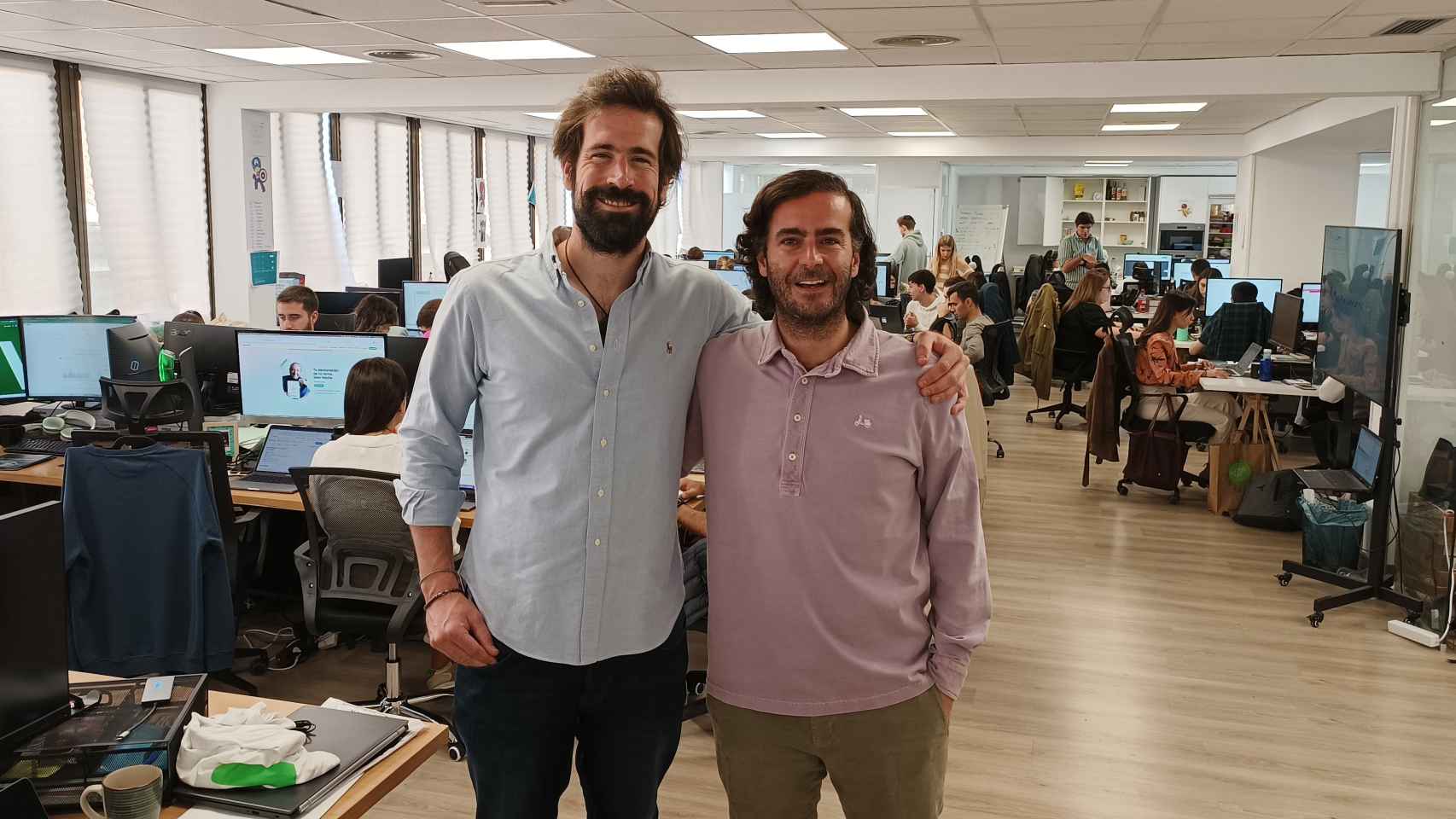 Enrique García (i.) y Álvaro Falcones (d.), cofundadores de Taxdown, en su oficina, repleta de trabajadores.