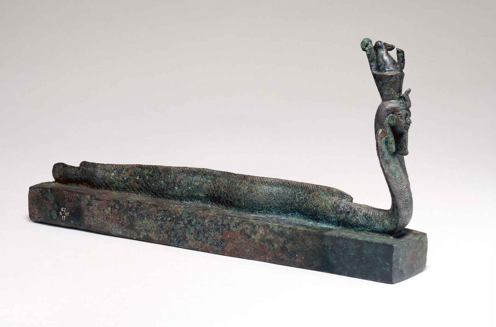Sarcófago de animal con una figura medio humana medio cobra con una corona doble, asociada al dios Atum.