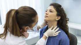 Una doctora revisa el tiroides a un mujer en el hospital.