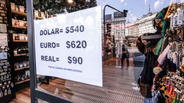 Un cartel en la entrada de un comercio de Buenos Aires indica el tipo de cambio del peso a tres monedas extranjeras.
