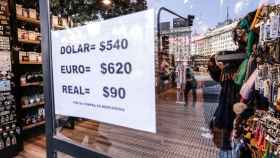 Un cartel en la entrada de un comercio de Buenos Aires indica el tipo de cambio del peso a tres monedas extranjeras.