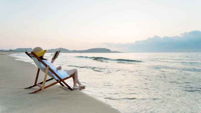 Una mujer disfrutando de la lectura en la playa. Foto: iStock.