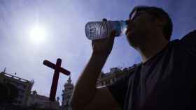 Una persona bebe agua en la plaza de las Tendillas frente a una Cruz de Mayo tras la activación de la alerta amarilla por las altas temperaturas, a 28 de abril de 2023 en Córdoba (Andalucía, España). Joaquin Corchero / Europa Press
