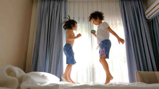 Niños jugando en la cama de un hotel.