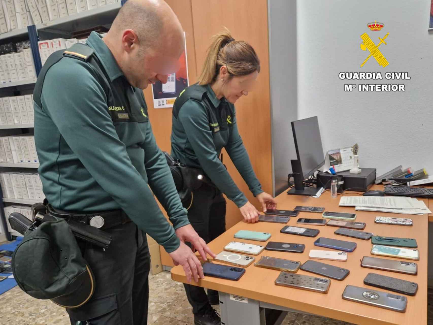 Dos agentes de la Guardia Civil junto a varios teléfonos móviles robados durante el Viñarock.