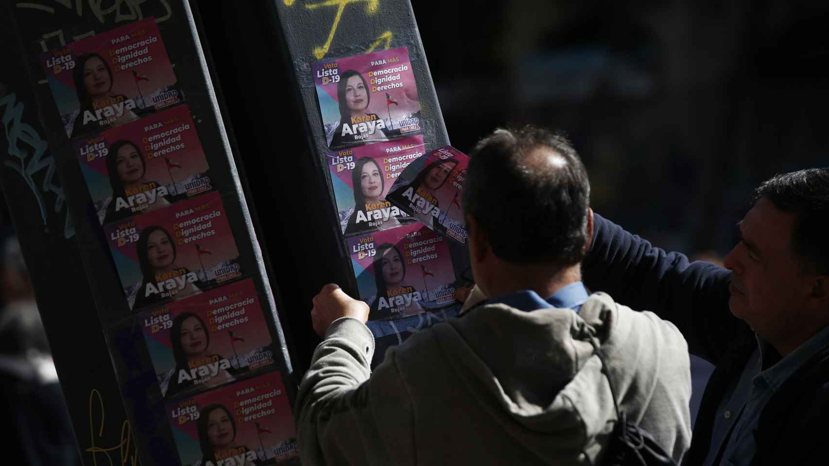 Un hombre pega propaganda electoral el 1 de mayo de 2023, en Santiago (Chile).