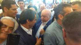 Un militante del PP tratando de arrancarse sus pines de la chaqueta para regalárselos a Aznar.