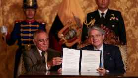 El presidente de Ecuador, Guillermo Lasso (dcha.), sostiene el decreto después de firmarlo el pasado jueves.