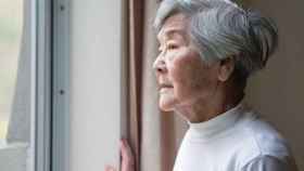 Una anciana china mira por la ventana.