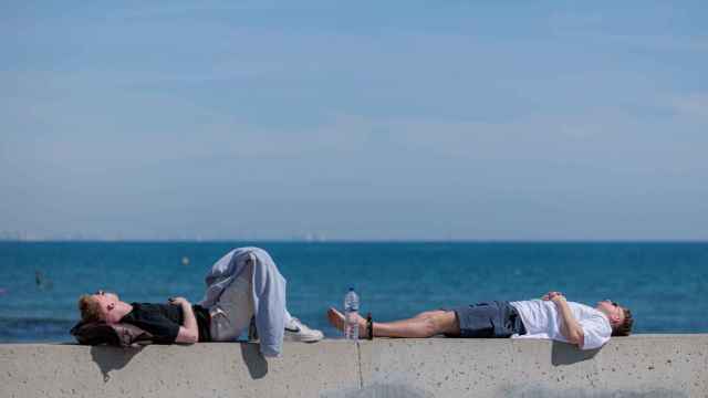 Dos personas descansan al sol en la playa de la Malvarrosa hace unos días.