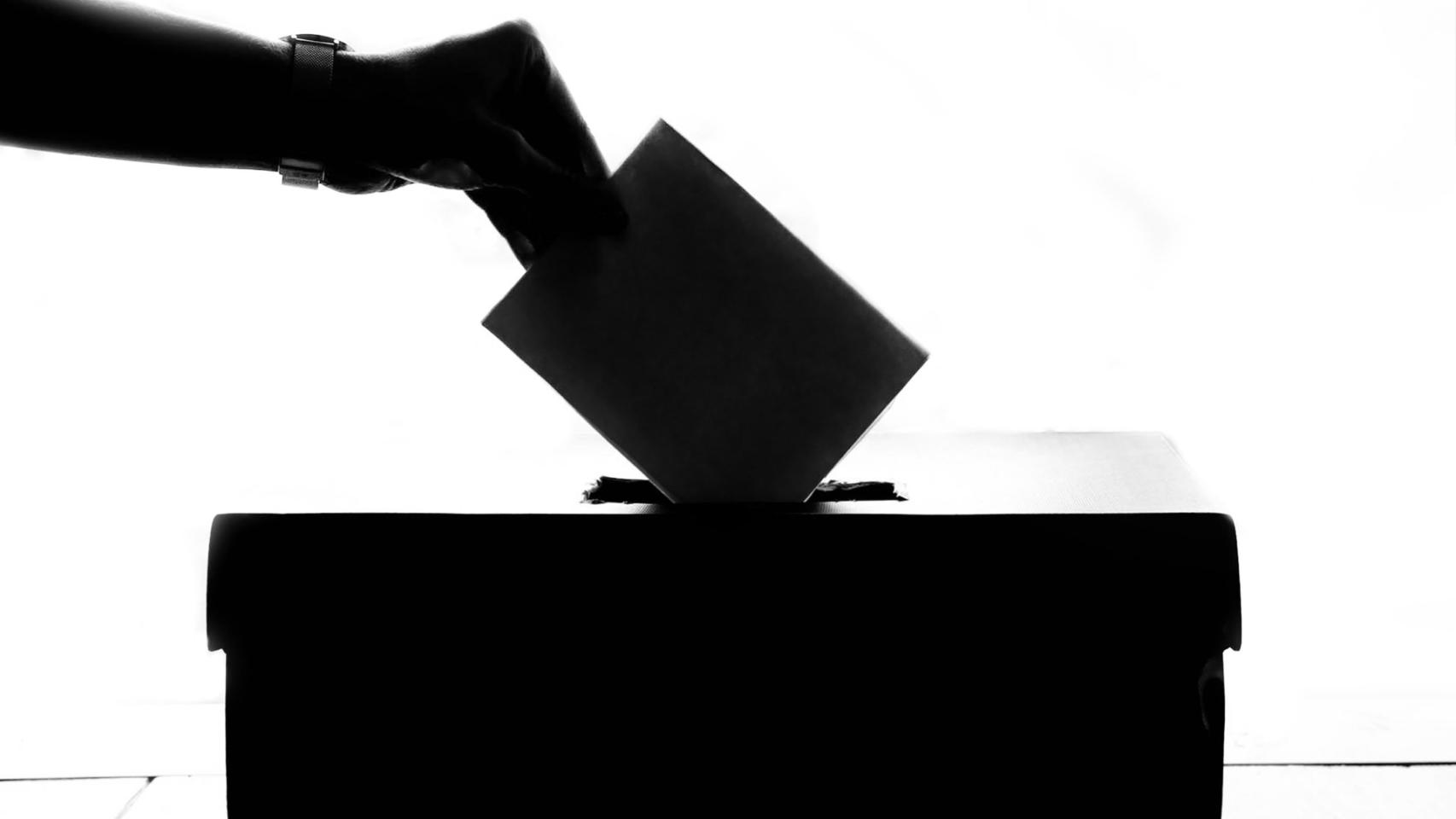 Una persona deposita su voto en una urna electoral.