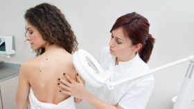 Una dermatóloga examina la piel de una mujer.