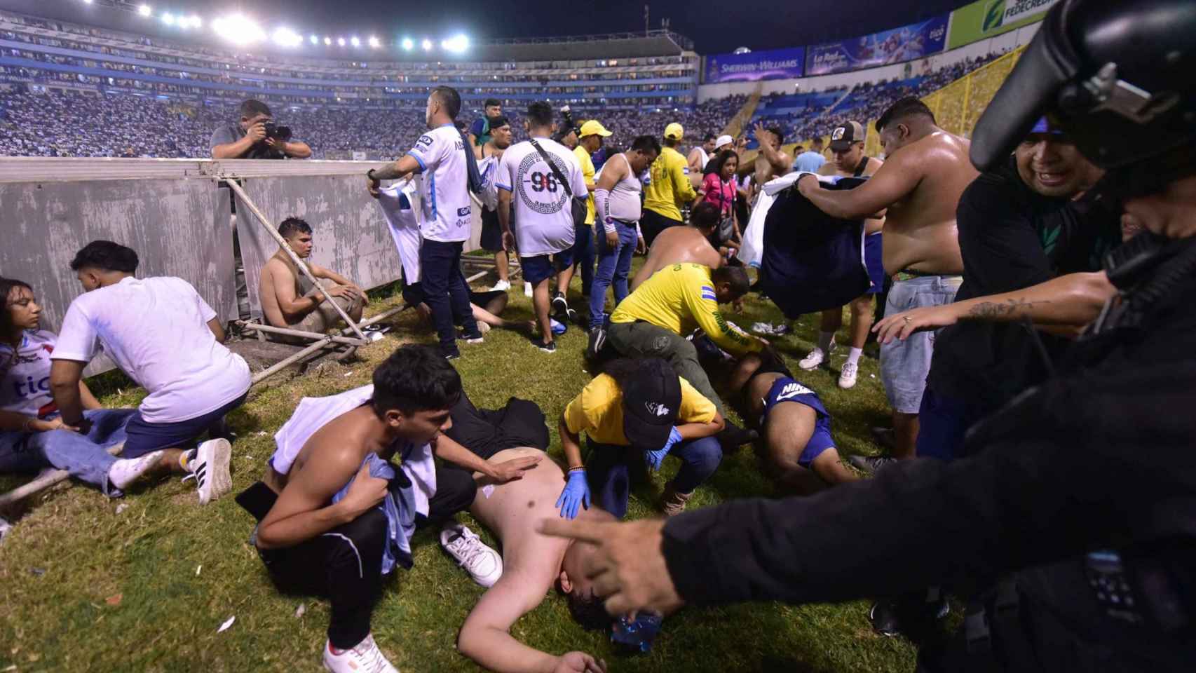 Aficinados auxilian a otros tras una estampida en un estadio de fútbol en El Salvador