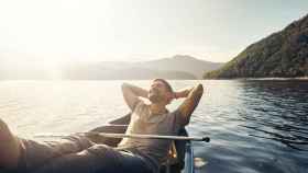 Un hombre feliz descansando en una barca al sol. Foto: iStock.