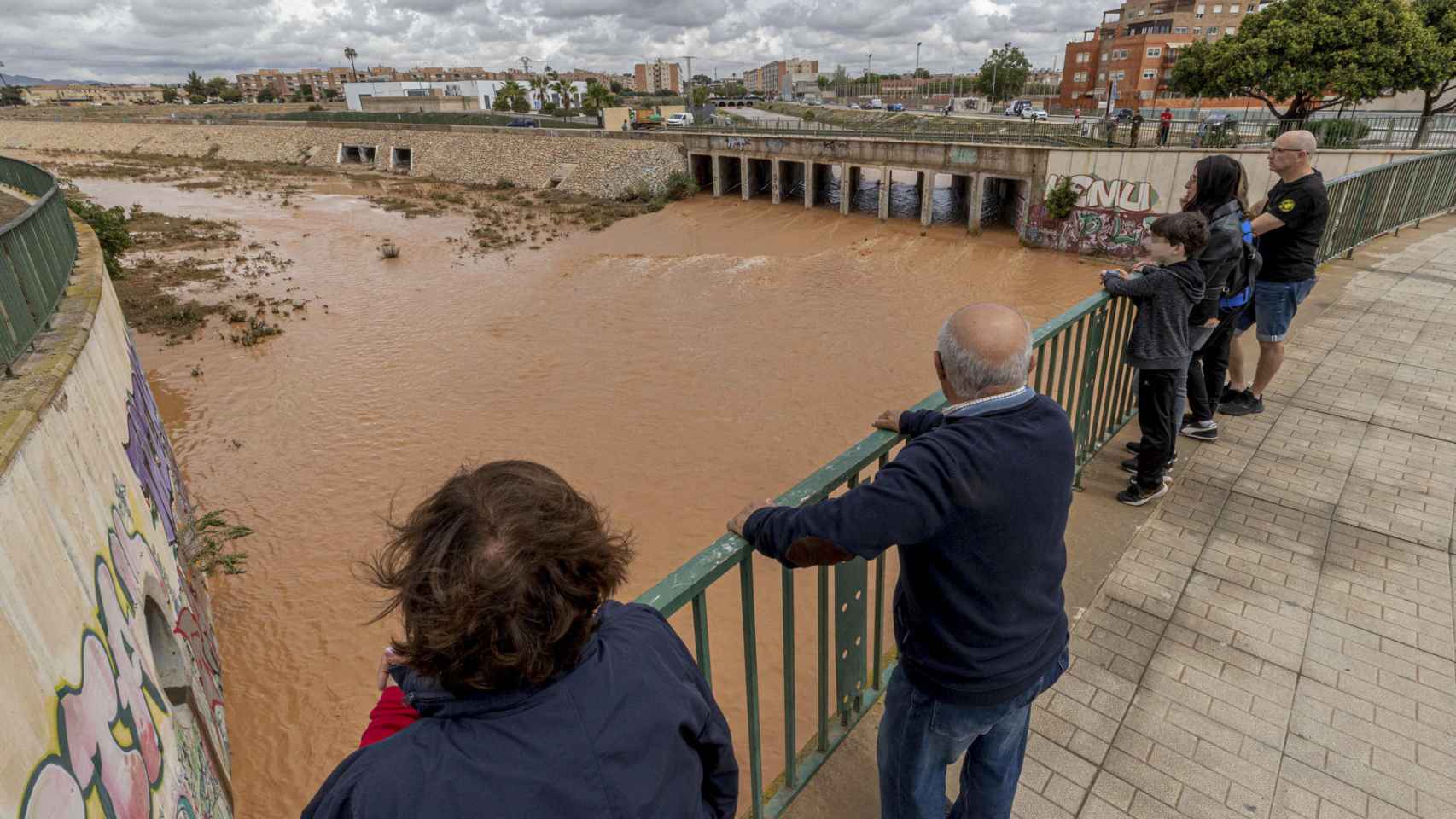 Varias personas observan la rambla de Benipila de Cartagena este martes tras las fuertes lluvias.