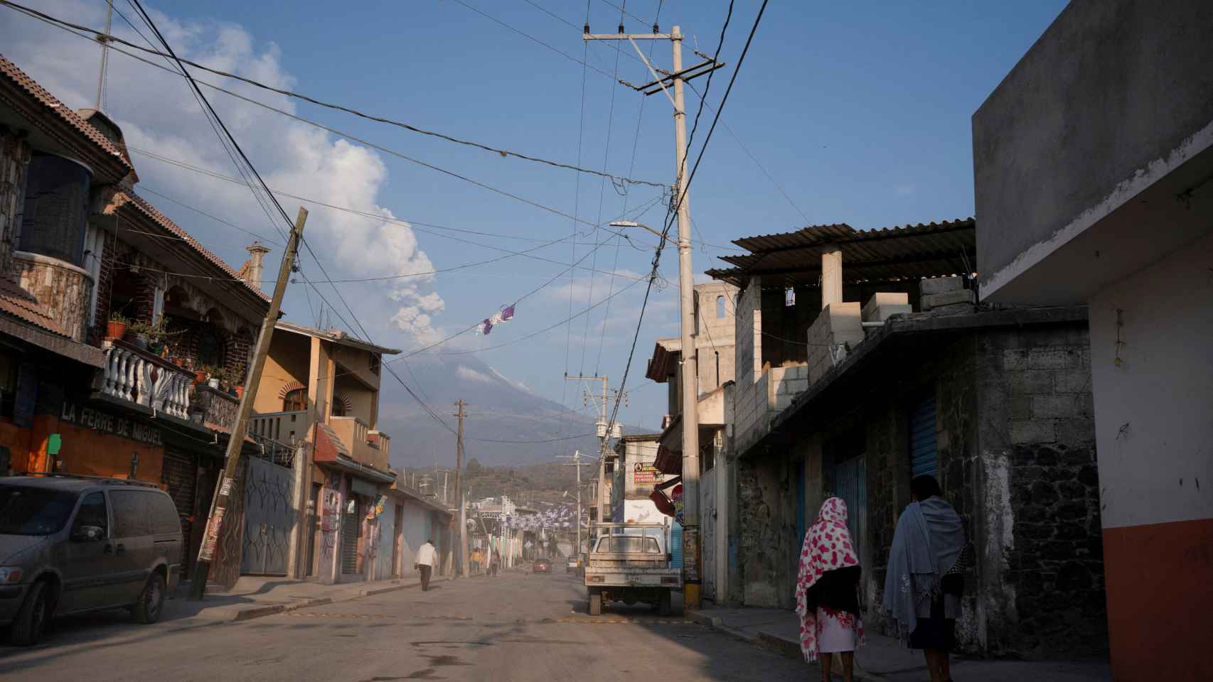 Vecinos de un municipio de Puebla conversan en una calle cubierta de ceniza volcánica.