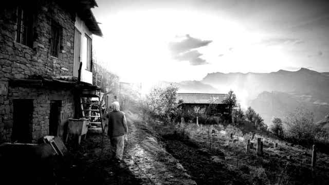 Una mujer camina por un pueblo montañoso.