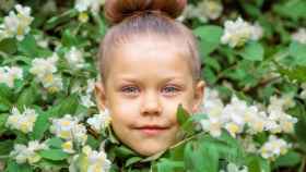 Una niña entre las plantas de su jardín.