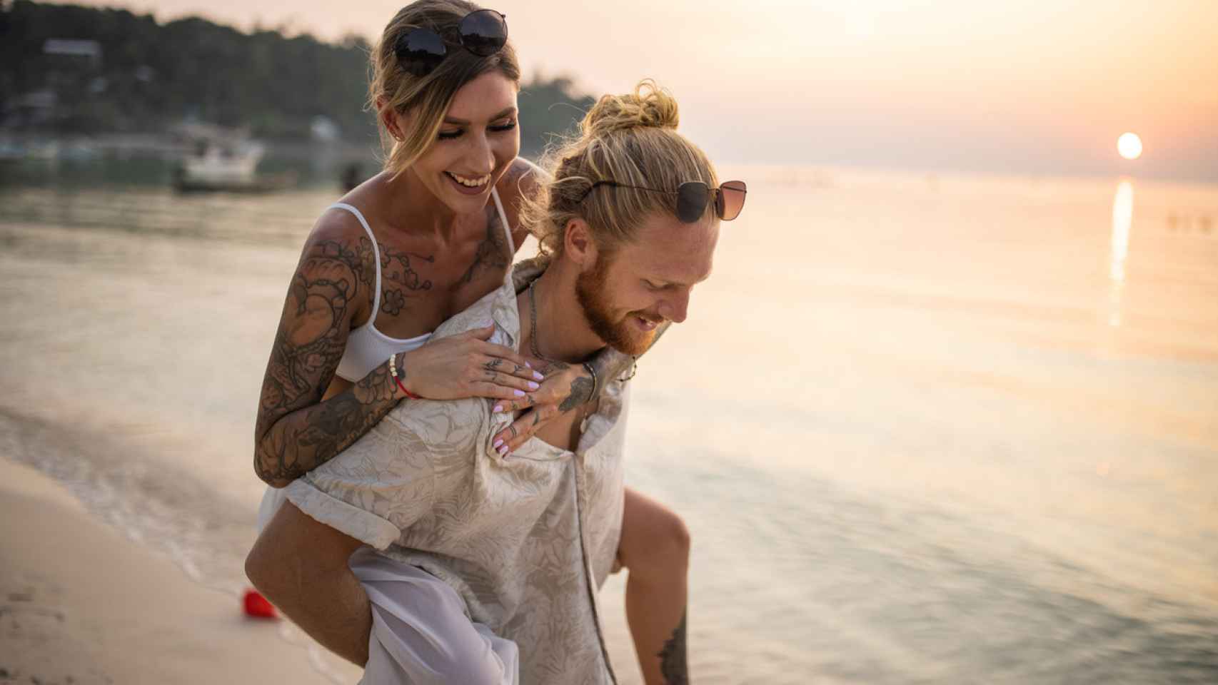Una pareja con tatuajes en la playa.