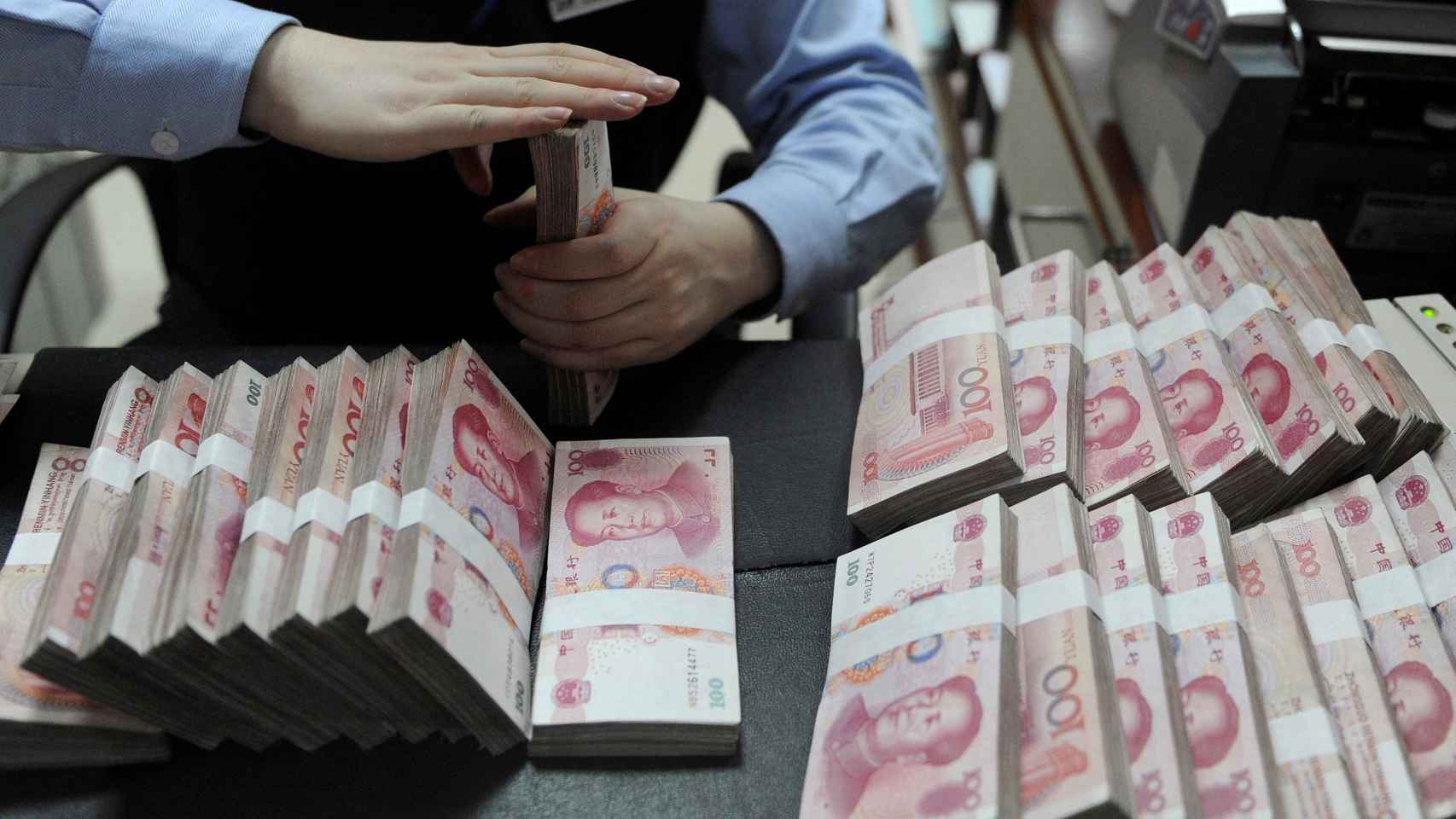 Un empleado cuenta billetes de 100 yuanes chinos en un banco de Hefei, en la provincia china de Anhui.