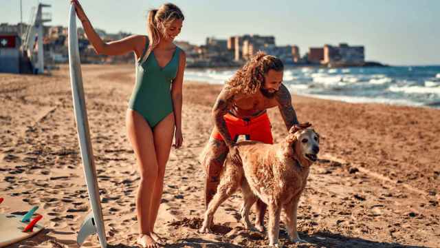 Una pareja con su perro de vacaciones en la playa.