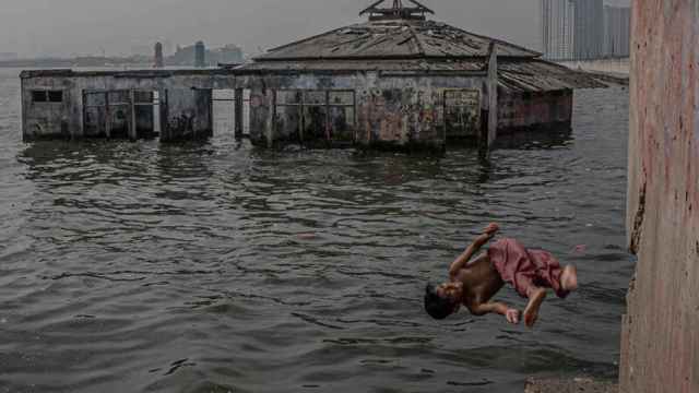 Un niño salta al agua cerca de la mezquita Wal Adhuna, en el área de Muara Baru, en el norte de Yakarta.