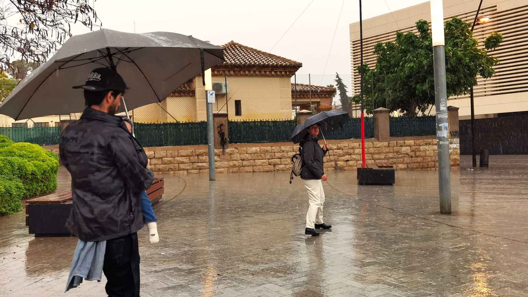 Una pareja cruza una plaza en Alicante bajo la lluvia este mayo.