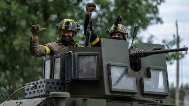 Militares ucranianos realizan gestos a bordo de un vehículo blindado en la ciudad de Vovchansk, en Járkov.