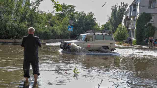 Voluntarios de la Cruz Roja conducen un automóvil en una calle inundada después de que se rompiera la represa de Nova Kakhovka, en Kherson