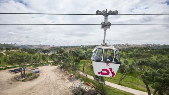 Varias personas disfrutan de un viaje en Teleférico de Madrid, por la Casa de Campo.